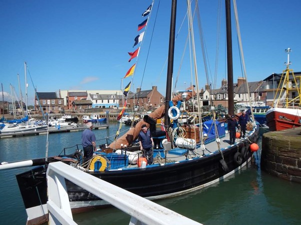 Four people manoeuvring Reaper in a harbour